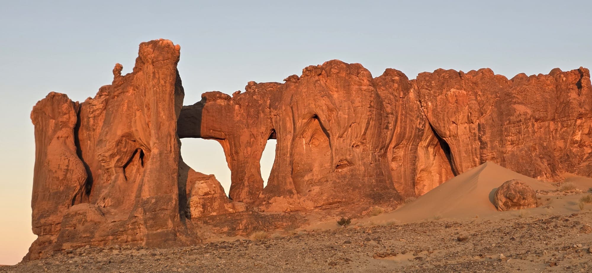 A natural sandstone window glowing in late-day desert light